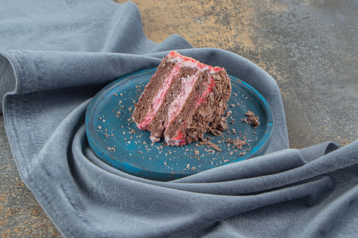 可口在一块布上的蓝色盘子上放一小块蛋糕烘焙糕点美味