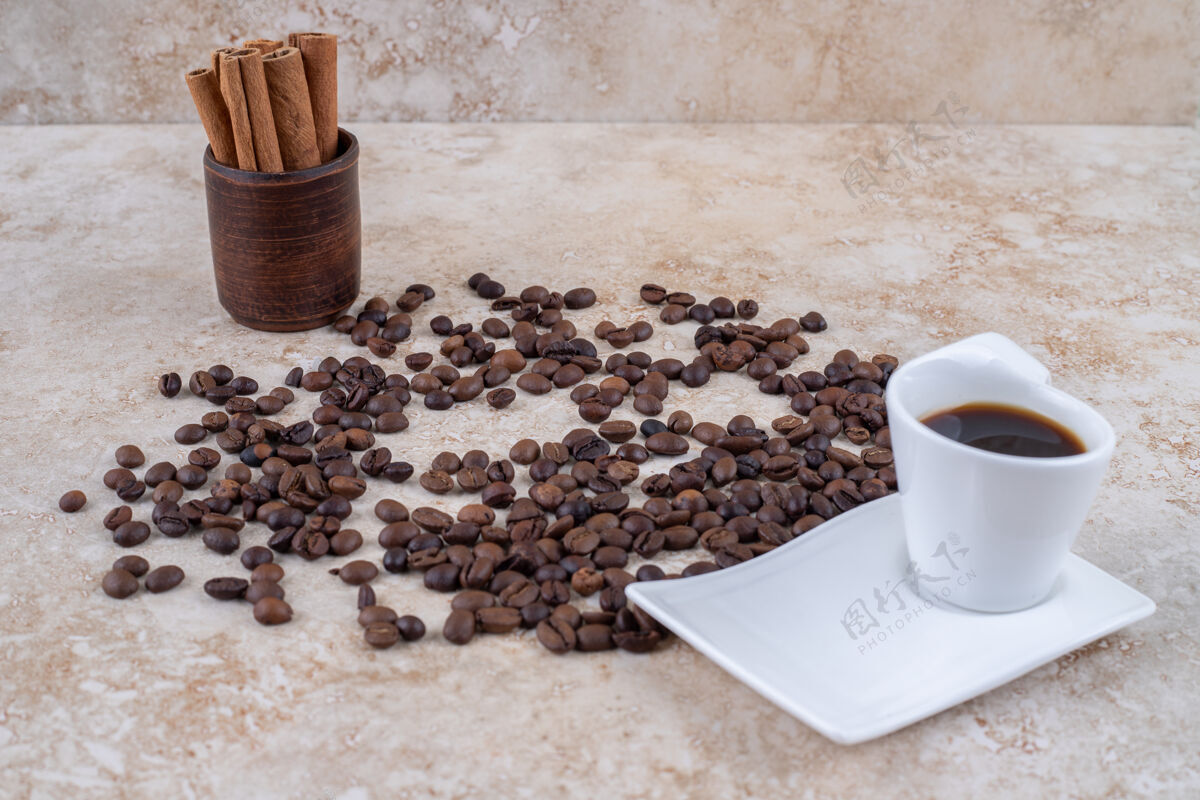 肉桂把一捆肉桂棒放在木杯旁 撒上咖啡豆和一杯咖啡美味芳香棒