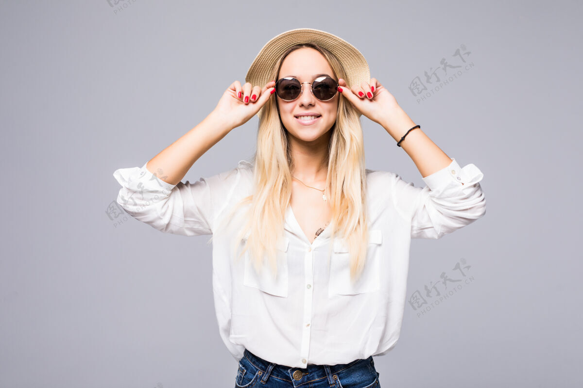 微笑灰墙上挂着一位戴草帽戴墨镜的迷人年轻女子的画像牛仔性感肖像