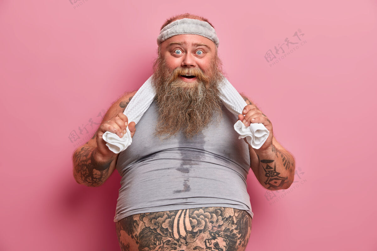 疲劳身材多汗的胖胡子男人的画像 在健身房做了筋疲力尽的运动后感到疲倦 大肚子从t恤衫上伸出来 手放在毛巾上 经常运动以减轻体重罗西肥胖毛巾