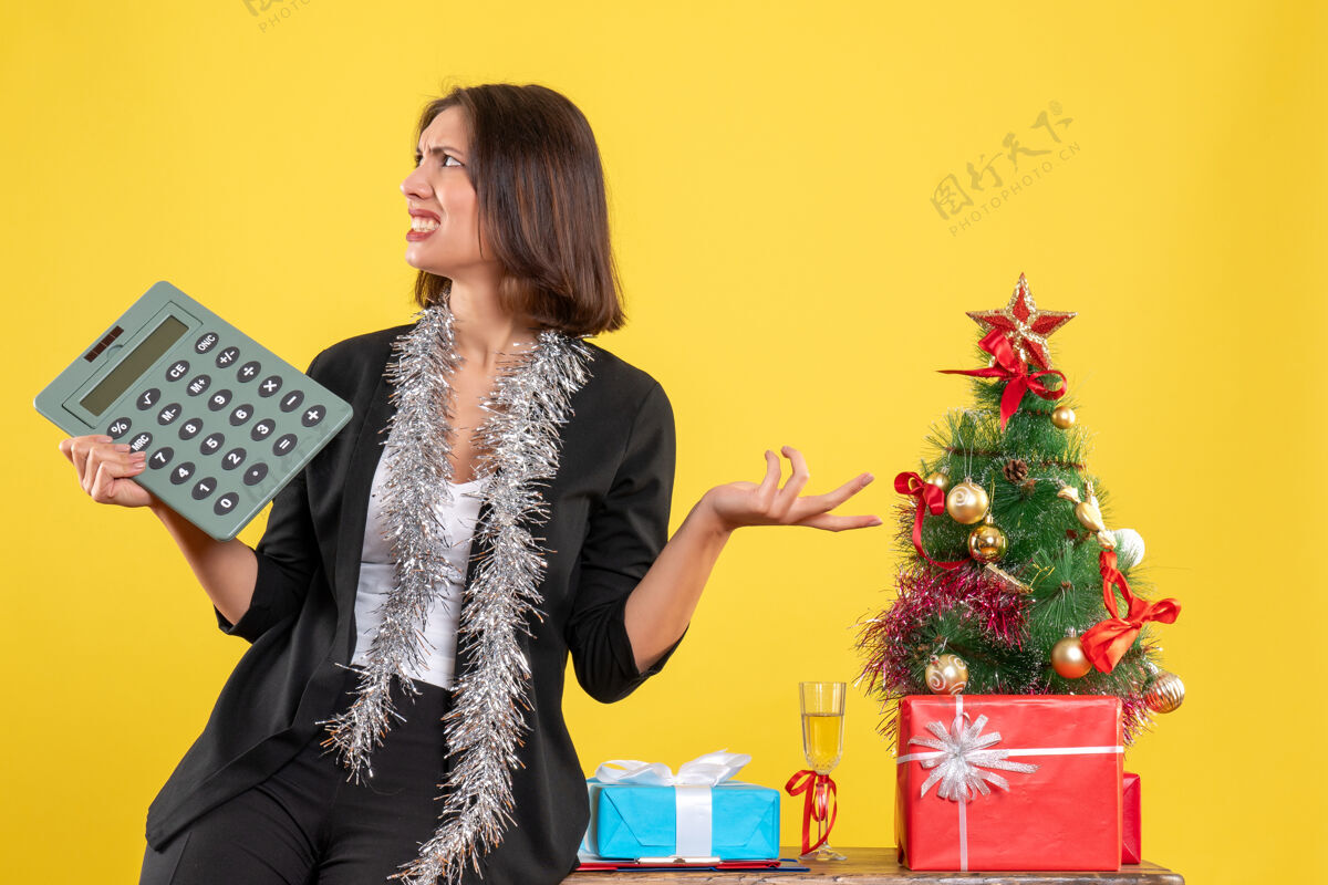 生活圣诞气氛紧张美丽的女士站在办公室里拿着计算器在办公室里的黄色计算器圣诞节美丽的女士