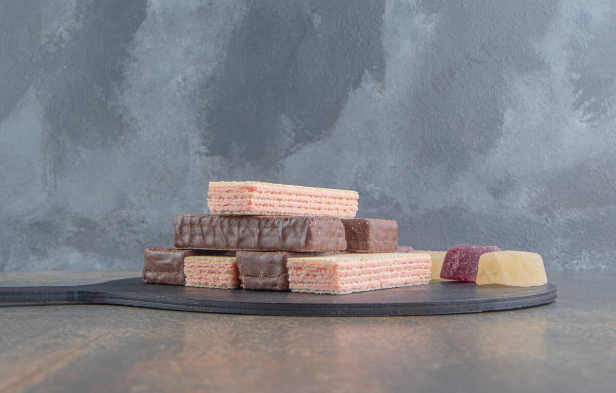 外套木桌上的小板上放着一堆带有marmelades的薄饼巧克力甜点美味