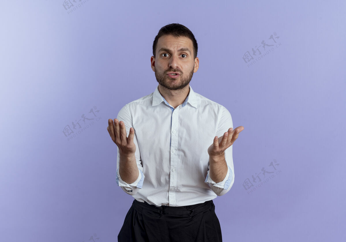 男人恼怒的帅哥在紫色的墙上拉着看起来孤立的手恼火手紫色