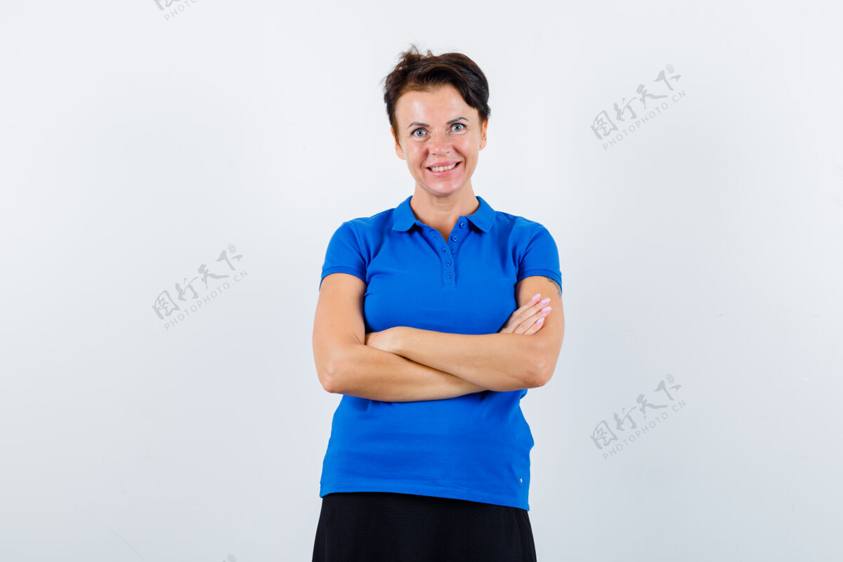 休闲穿蓝色t恤的成熟女性交叉双臂站立 看起来很自信 正面视图皮肤护理头发退休