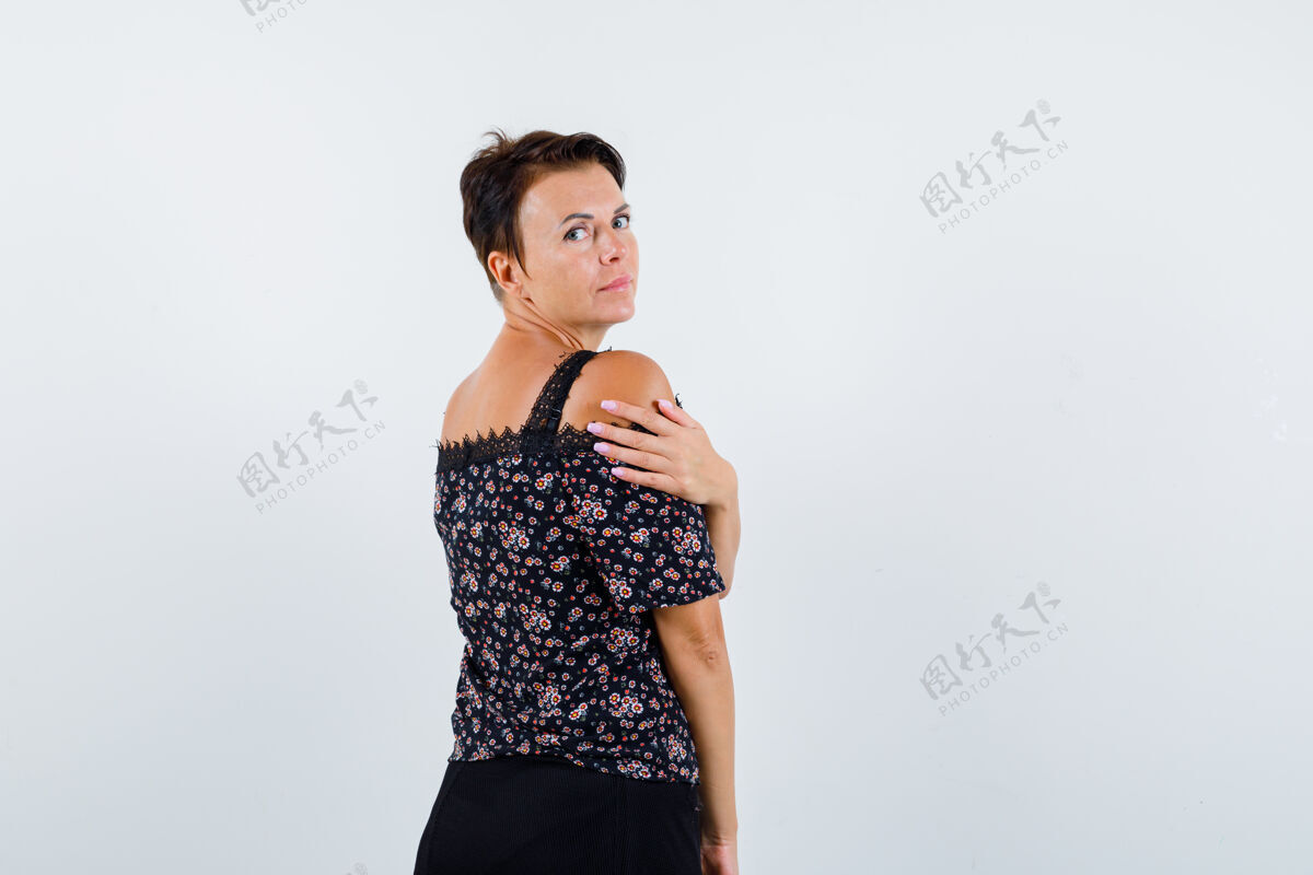 肖像穿着花衬衫和黑色裙子的成熟女性 一边摆姿势一边回头看 看起来很吸引人 正面视图活跃肩膀商务