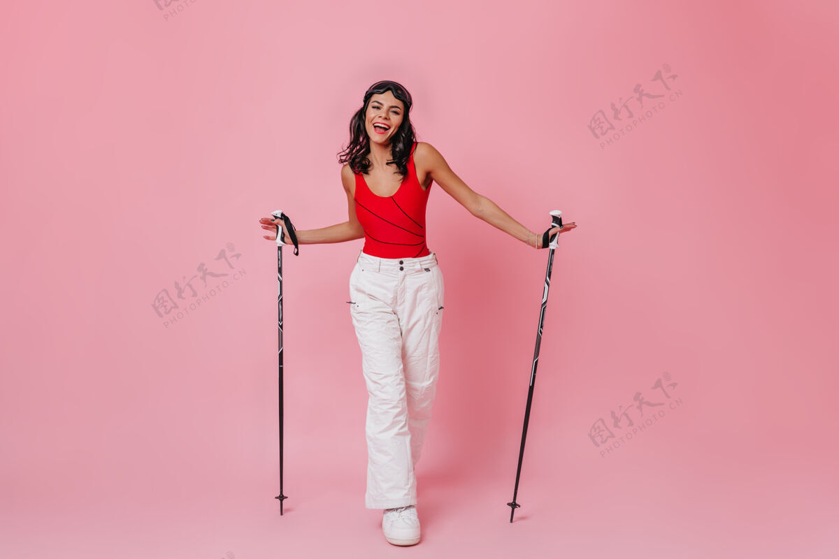 表情快乐的女人拿着粉红色背景的滑雪杆欢呼成人女士