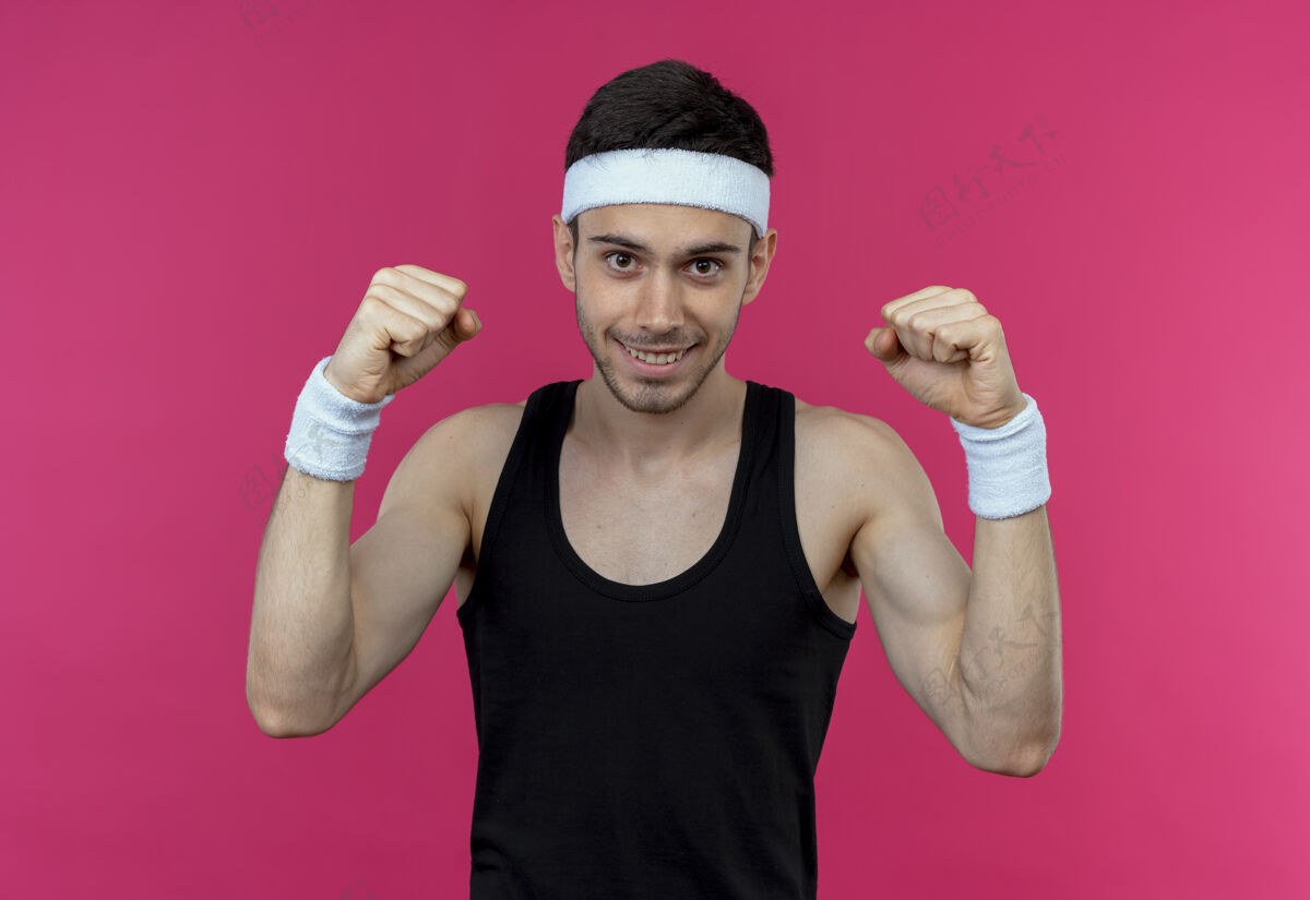 运动戴着头巾的年轻运动型男子举起拳头 站在粉红色的背景上愉快地微笑着站立举起欢呼