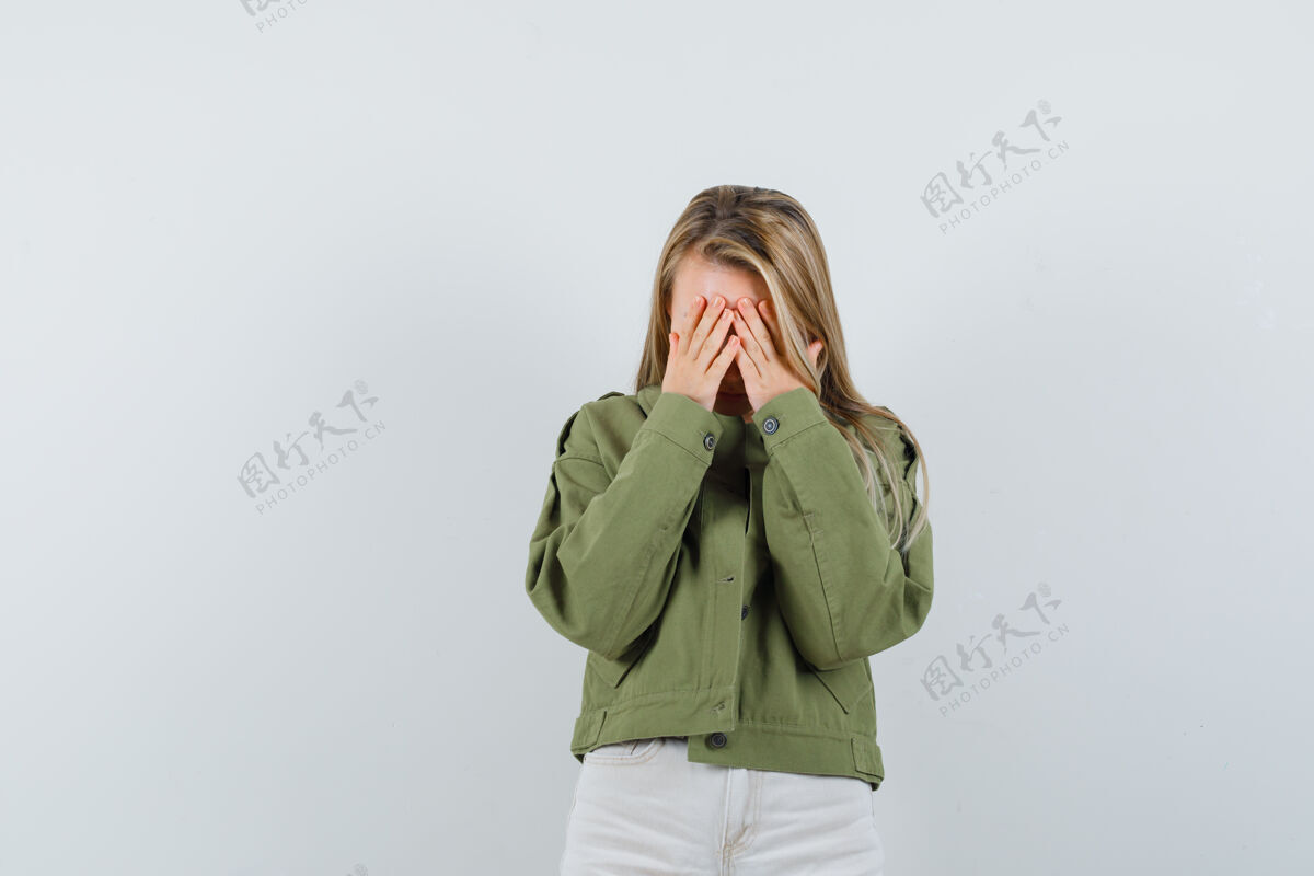 健康年轻女士用手捂着脸 穿着夹克 裤子 看上去很苦恼正视图年轻女士脸