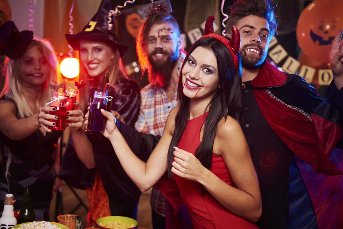 女人年轻朋友在万圣节派对上玩得开心服装酒精男人