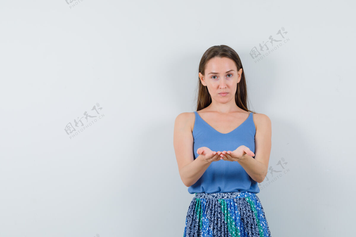 手穿着蓝色上衣 裙子的年轻女士 双手合十 好像拿着什么东西 看起来很专注前视图魅力喜欢女士