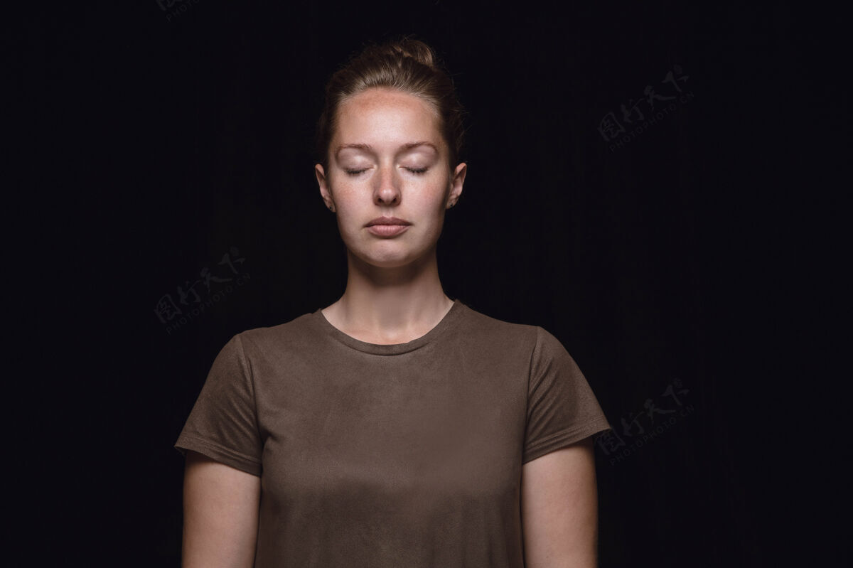 思想在黑色工作室背景上拍摄的年轻女子的特写肖像闭着眼睛拍摄的女模特真实的情感体贴面部表情 人性和情感观念表情孤独拍摄