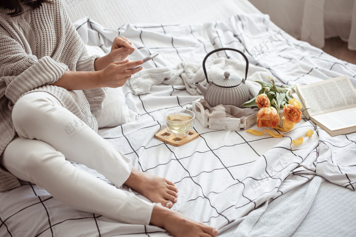 女人一个女人在床上休息 茶 一本书和一束郁金香休息茶床