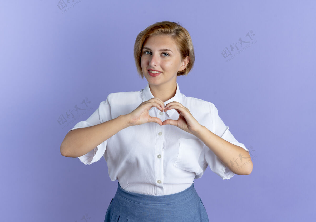 手年轻的微笑金发俄罗斯女孩手势心手标志孤立的紫色背景与复制空间手势俄罗斯年轻