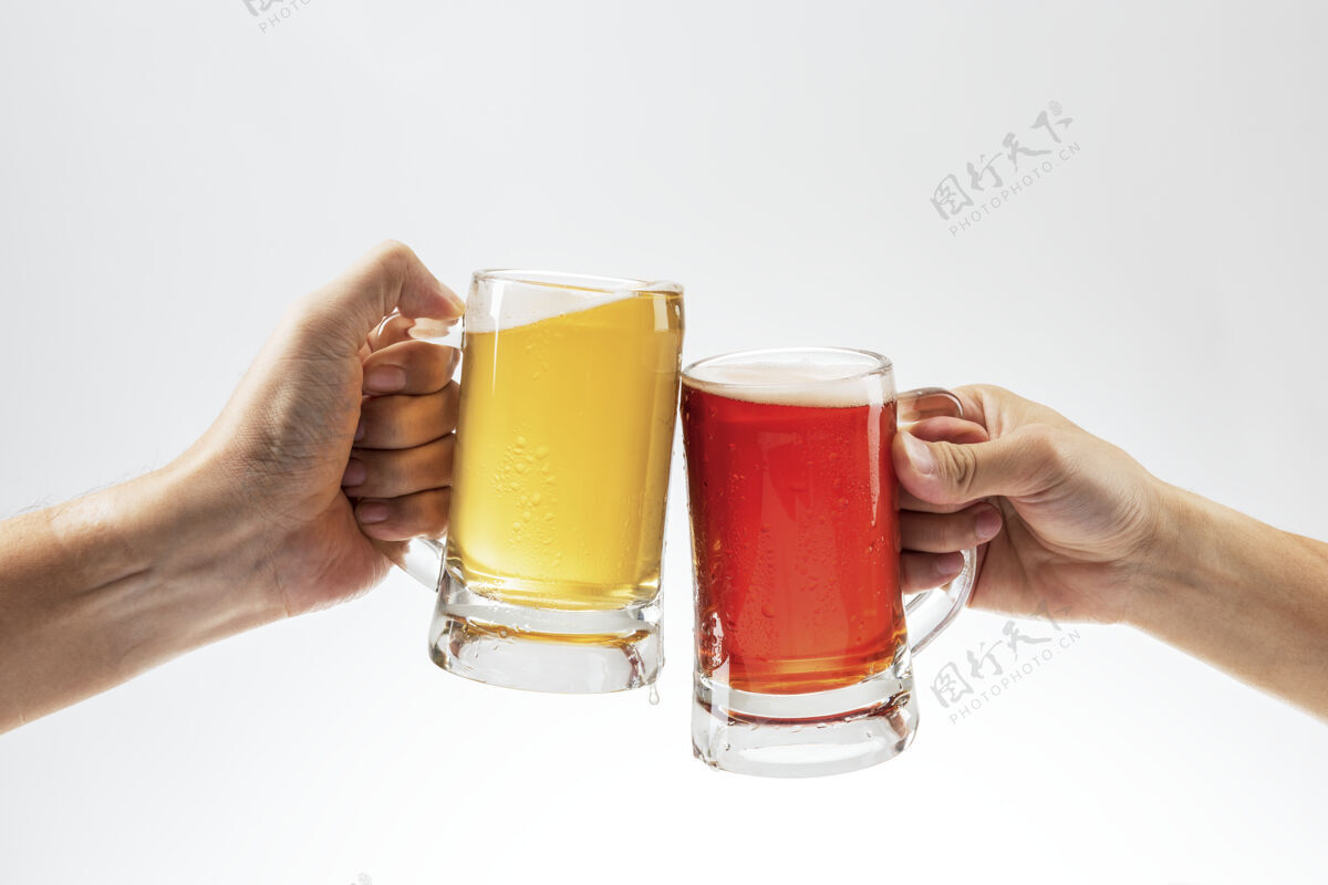 泡沫在白色背景上用啤酒敬酒的男人们啤酒厂玻璃酒