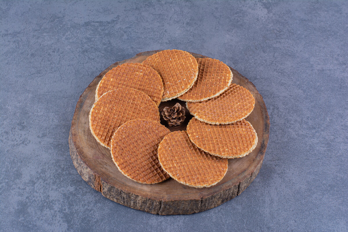 焦糖在一块石头上的一个木制盘子里隔离着松果高质量的照片华夫饼饼干美味