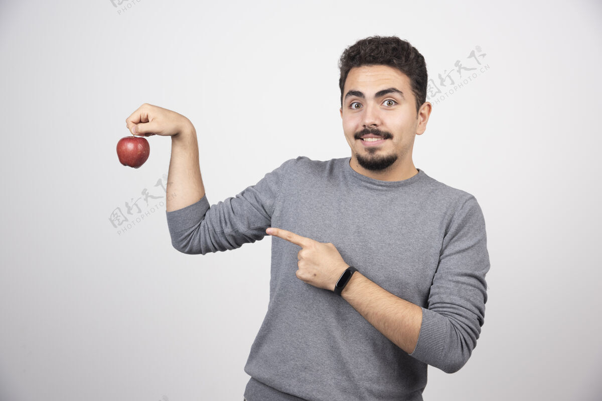 可爱黑发男人指着灰色的红苹果自然男性举行