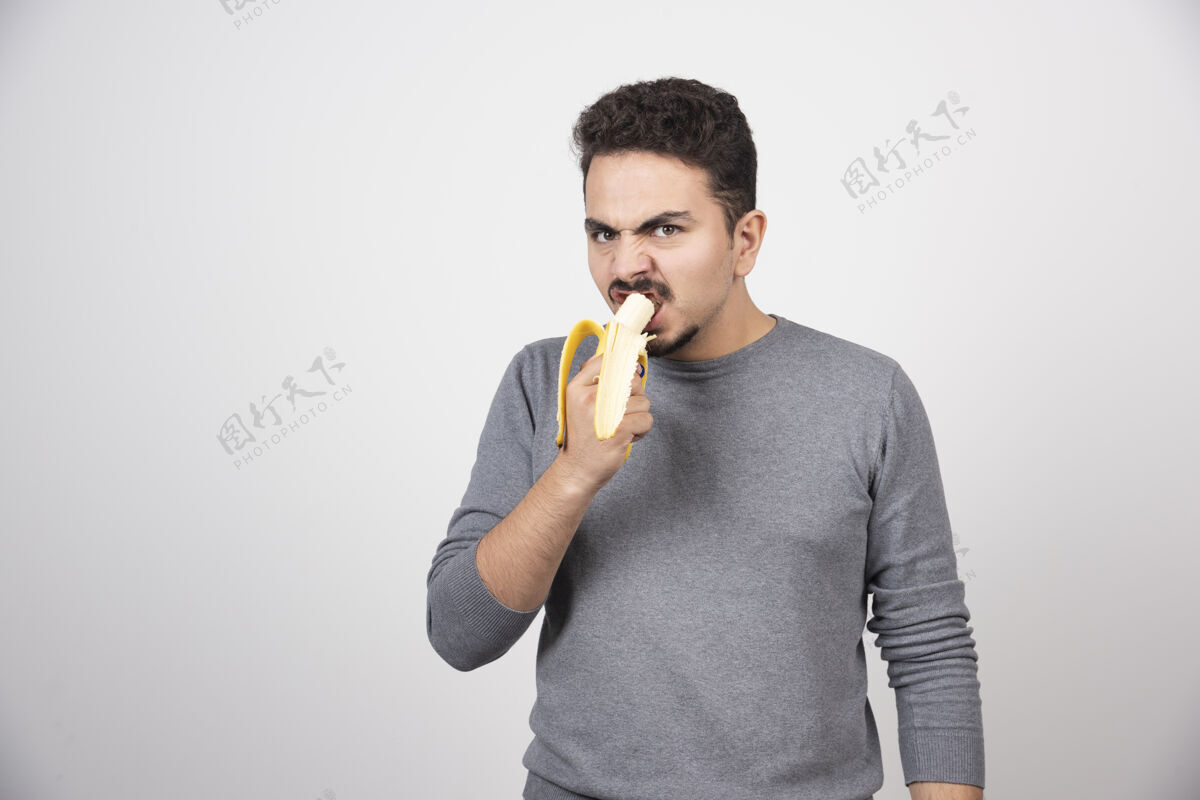 符号愤怒的年轻人在白墙上吃香蕉肖像脸男性