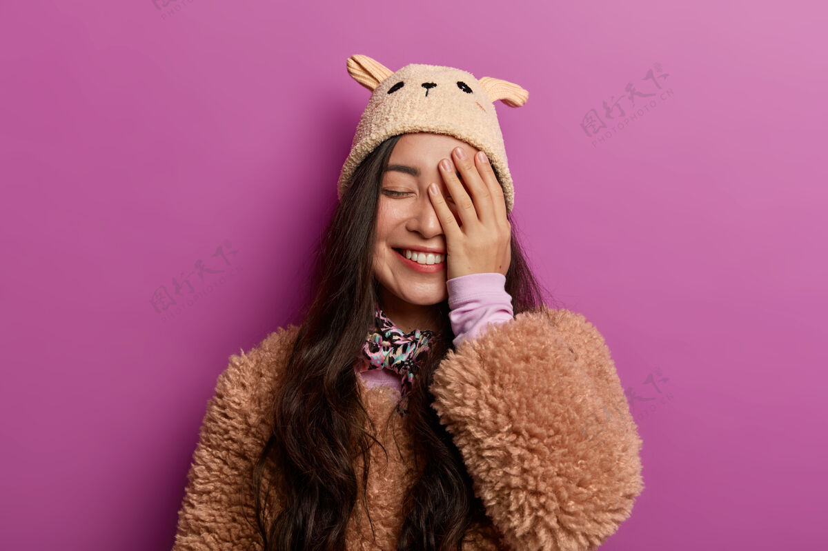 满意积极真诚的年轻女子欢笑着 遮住半张脸 闭上眼睛 穿着冬装女士亚洲人温柔
