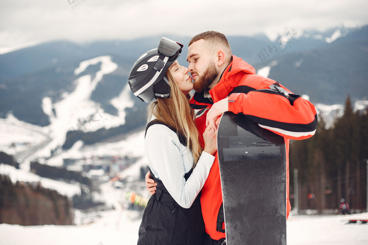 高山穿着滑雪板套装的情侣在山上运动的人手里拿着滑雪板在地平线上运动的概念女人下雪寒冷