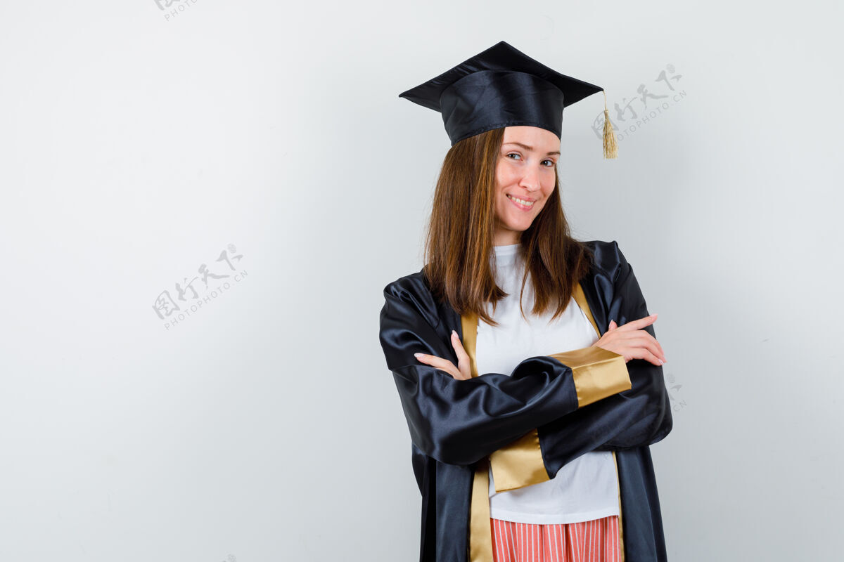 手臂毕业的女人穿着休闲服 穿着制服 双臂交叉站着 看起来很自信 前视帽子年轻大学