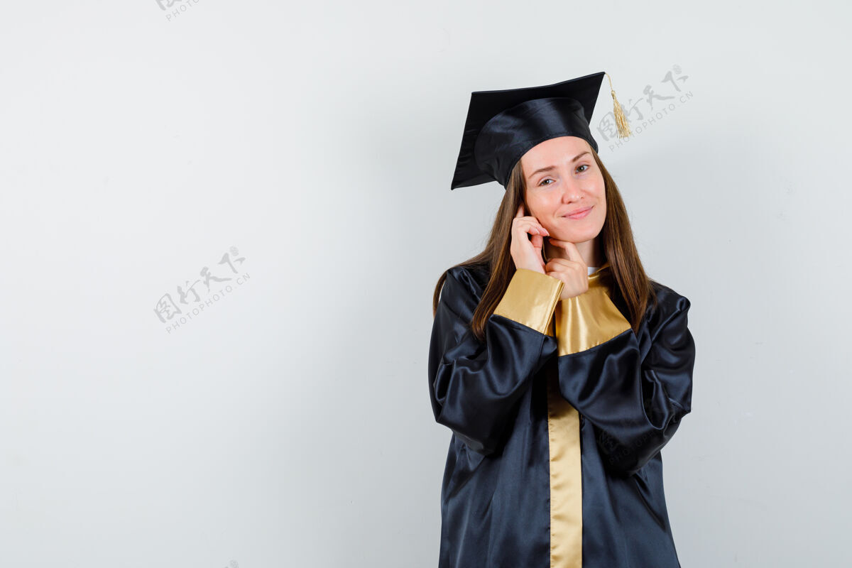 健康年轻的女毕业生穿着学院服站着摆姿势 看起来很迷人 前视图自然女性姿势