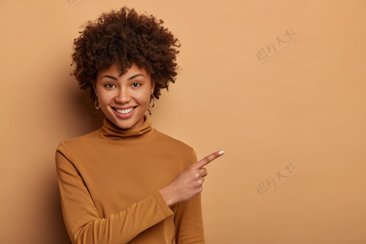 毛衣一位留着非洲式发型 面容友好的女士 在复印区右指右指 展示新产品 做促销广告高兴女性地点