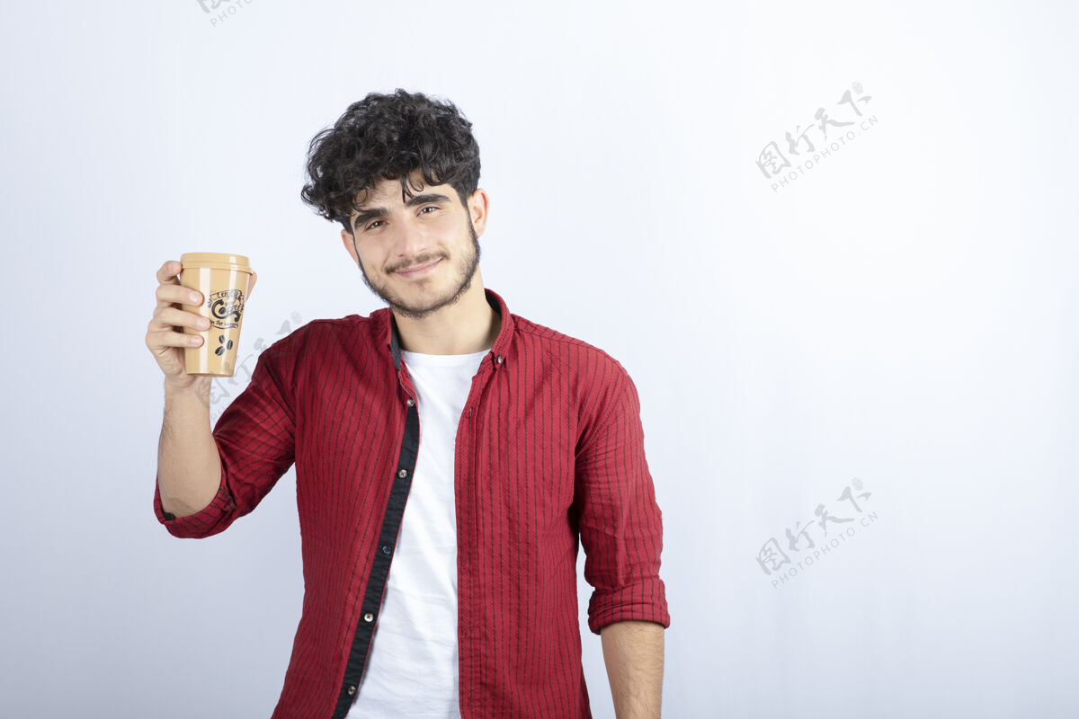 年轻照片中的黑发男子拿着一杯咖啡在白墙上休息黑发模特休息