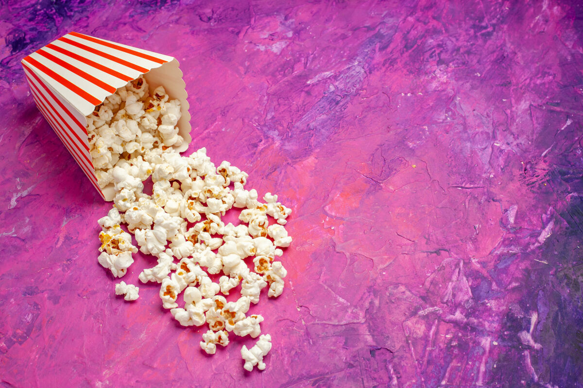 前面正面看新鲜的爆米花放在粉红色的桌子上电影院的玉米片颜色玉米电影院新鲜爆米花