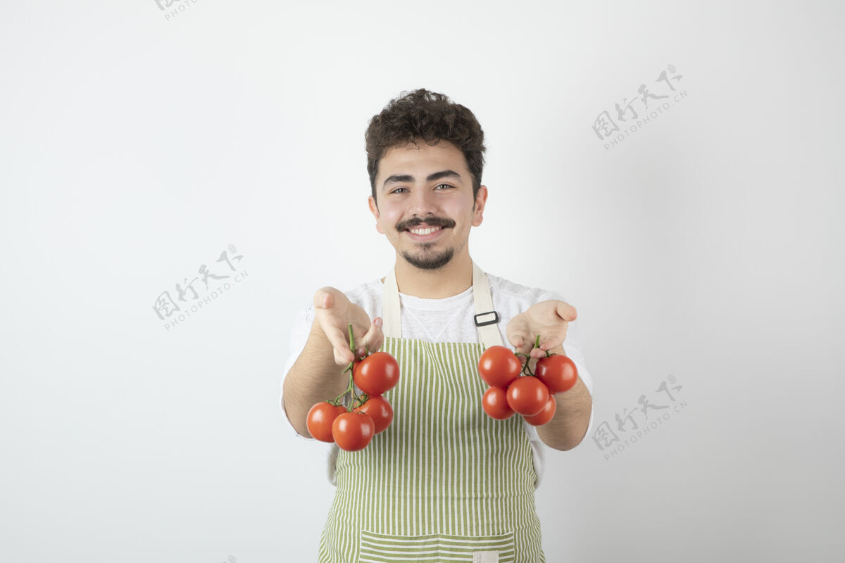 成人一个面带微笑的家伙拿着一堆新鲜的西红柿 看着摄像机西红柿工人白人