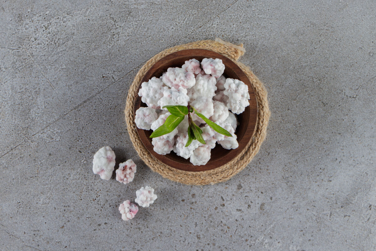 新鲜的石头桌上放满了薄荷叶甜白糖果的木碗木头食物糖果