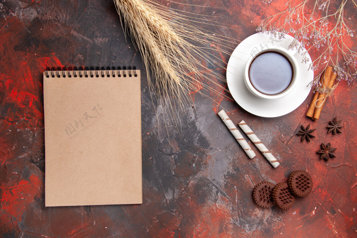 饼干顶视图一杯茶加巧克力饼干放在深色桌子上茶饼干饼干茶杯工具笔