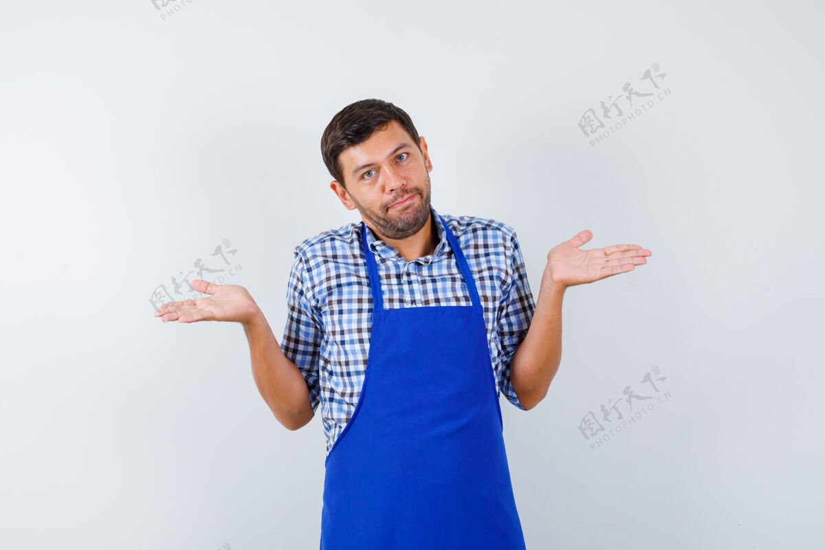 男士穿着蓝色围裙和衬衫的年轻男厨师男士烹饪年轻