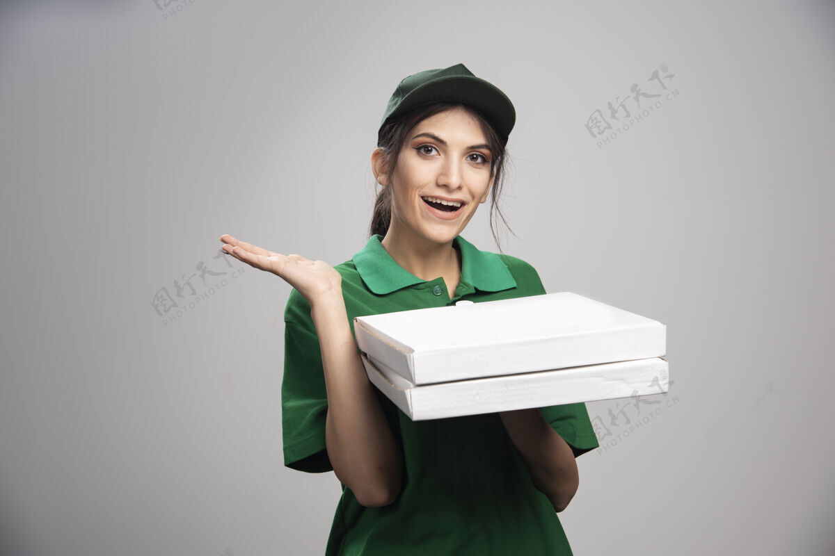 食物送货员拿着披萨盒摆姿势帽子雇员工人