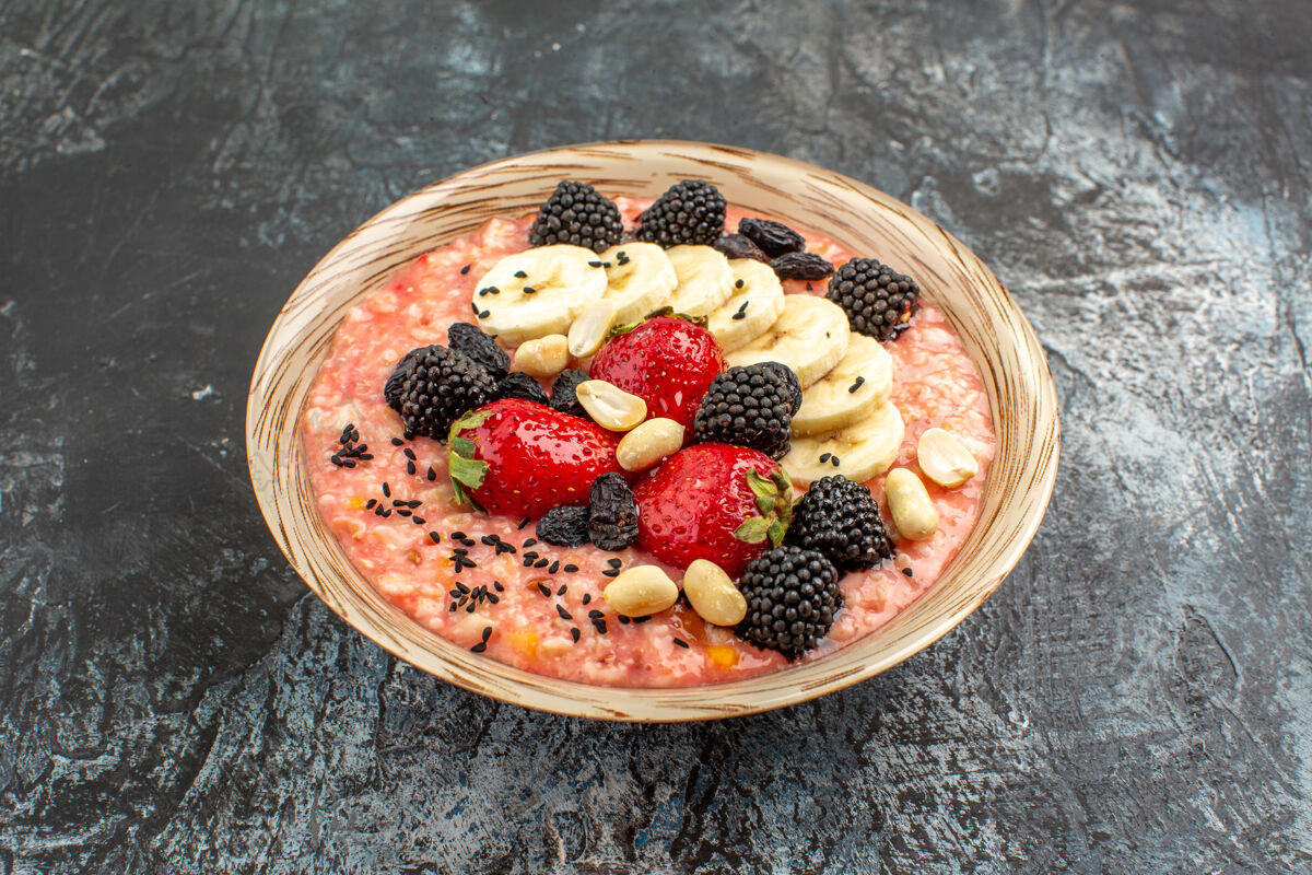 水果正面图深色餐桌上水果切片的穆斯利健康麦片早餐草莓深色浆果
