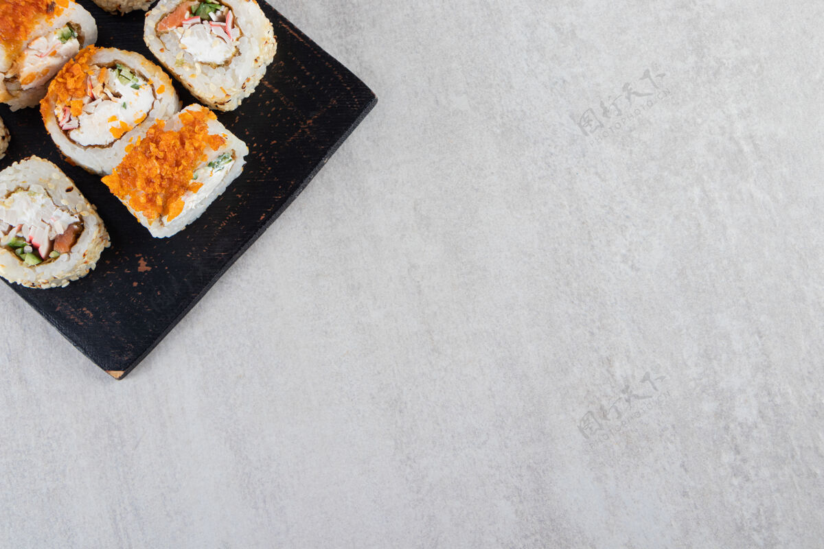 海鲜新鲜美味的寿司卷放在深色木板上饭寿司卷