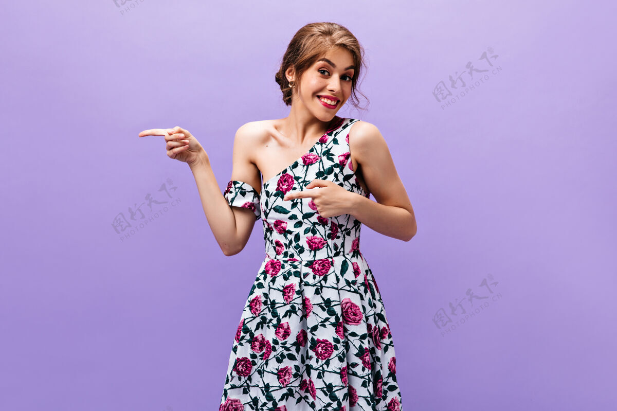 花漂亮的女人穿着花裙子指着地方发短信漂亮时髦的女孩穿着夏装留着清凉的发型微笑着紫色休闲年轻