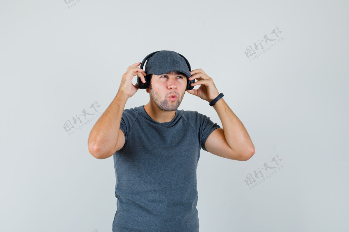 电脑网络摄像头戴着头戴耳机 头戴t恤帽 神情沉思的年轻男性兴奋的小自信虚拟