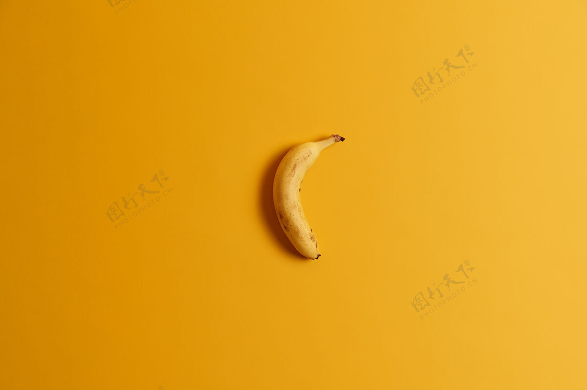 香蕉一根成熟的香蕉在黄色背景上的俯视图美味的热带水果为您的美味早餐或零食全香蕉即食有益的营养产品 富含维生素小吃生的营养素