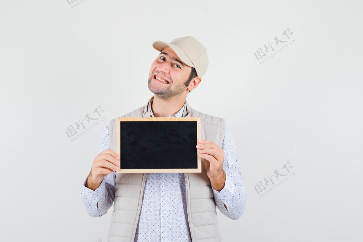 男人穿着米色夹克和帽子的年轻人手里拿着黑板 看上去很高兴 正对着窗外男人时尚脸