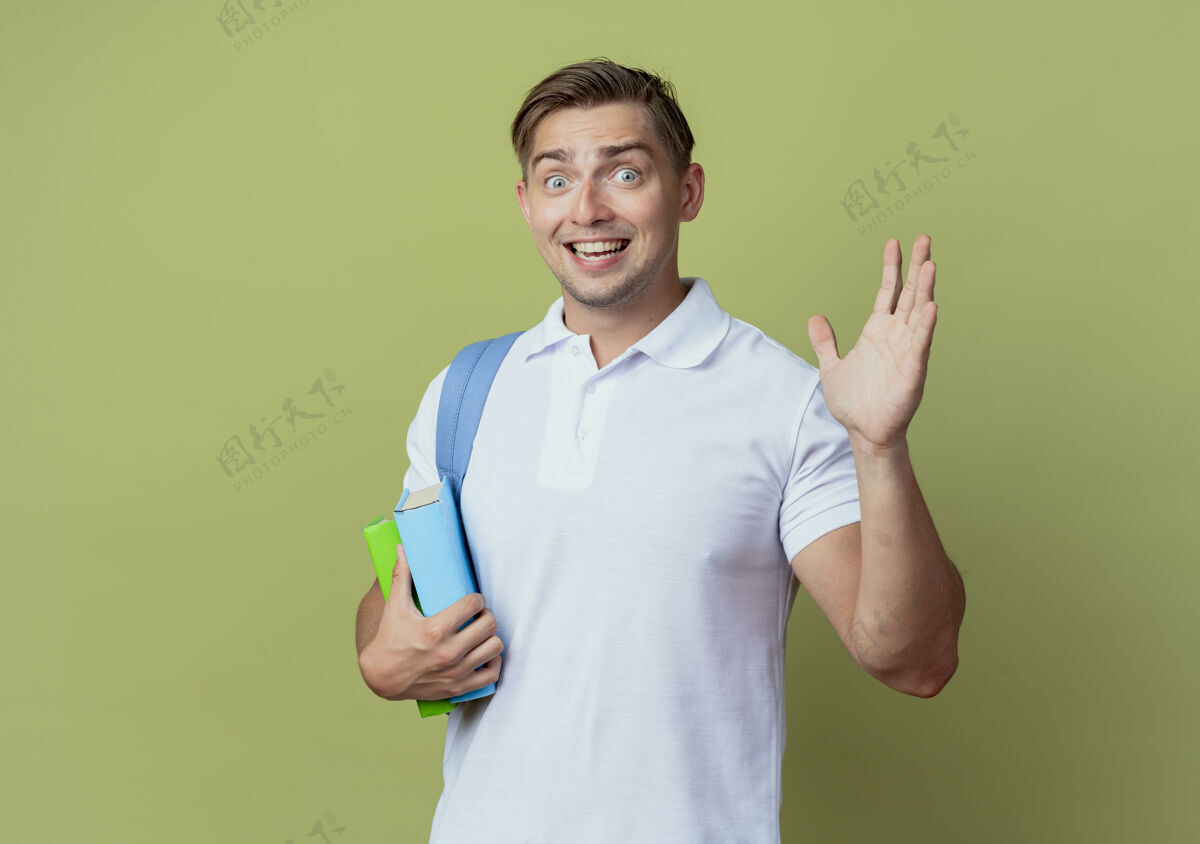 男快乐的年轻帅气的男学生背着书包 在橄榄绿的背景上单独打招呼抱包穿