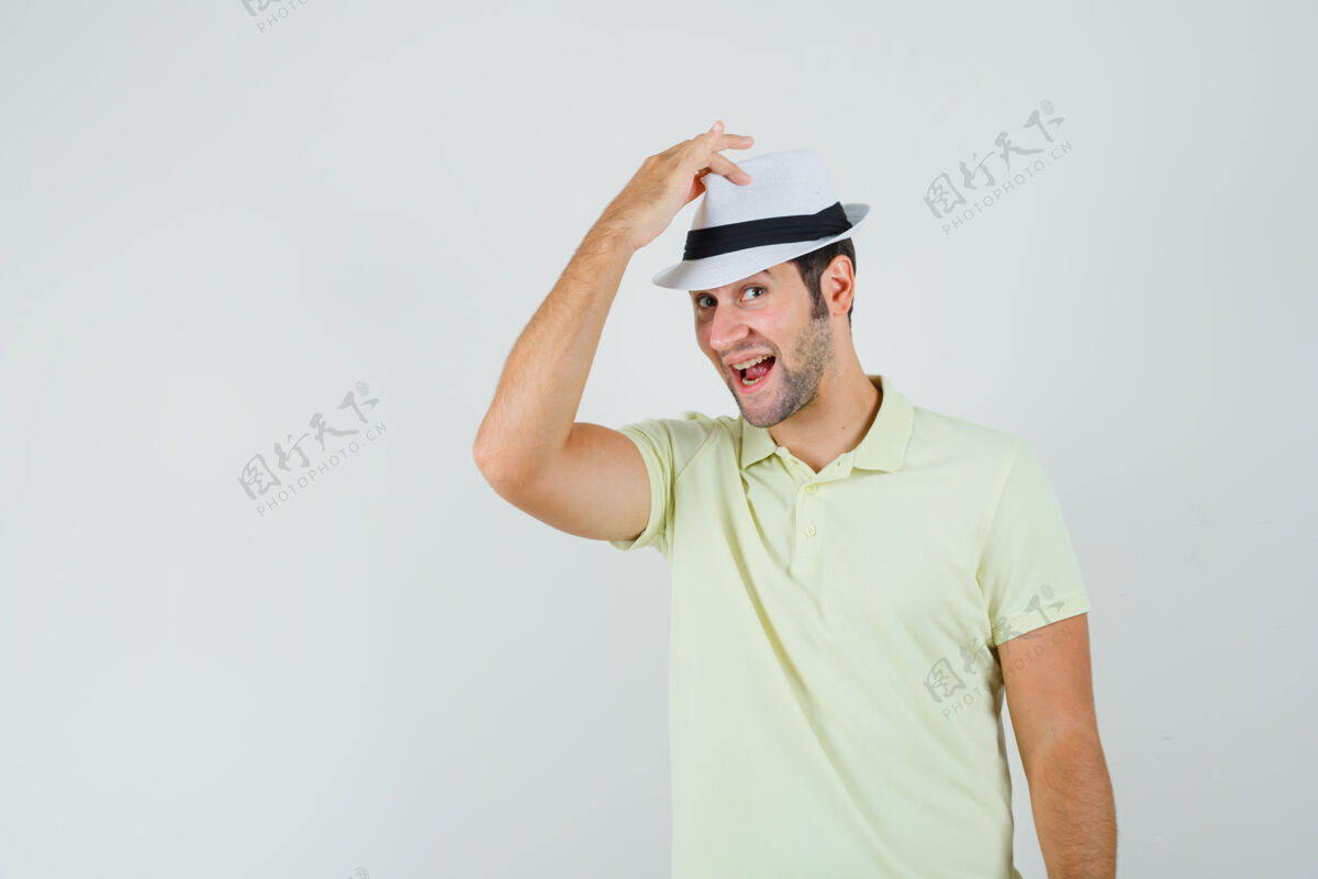衬衫一个穿着t恤的年轻人手拿帽子 看上去很帅帽子T恤自信