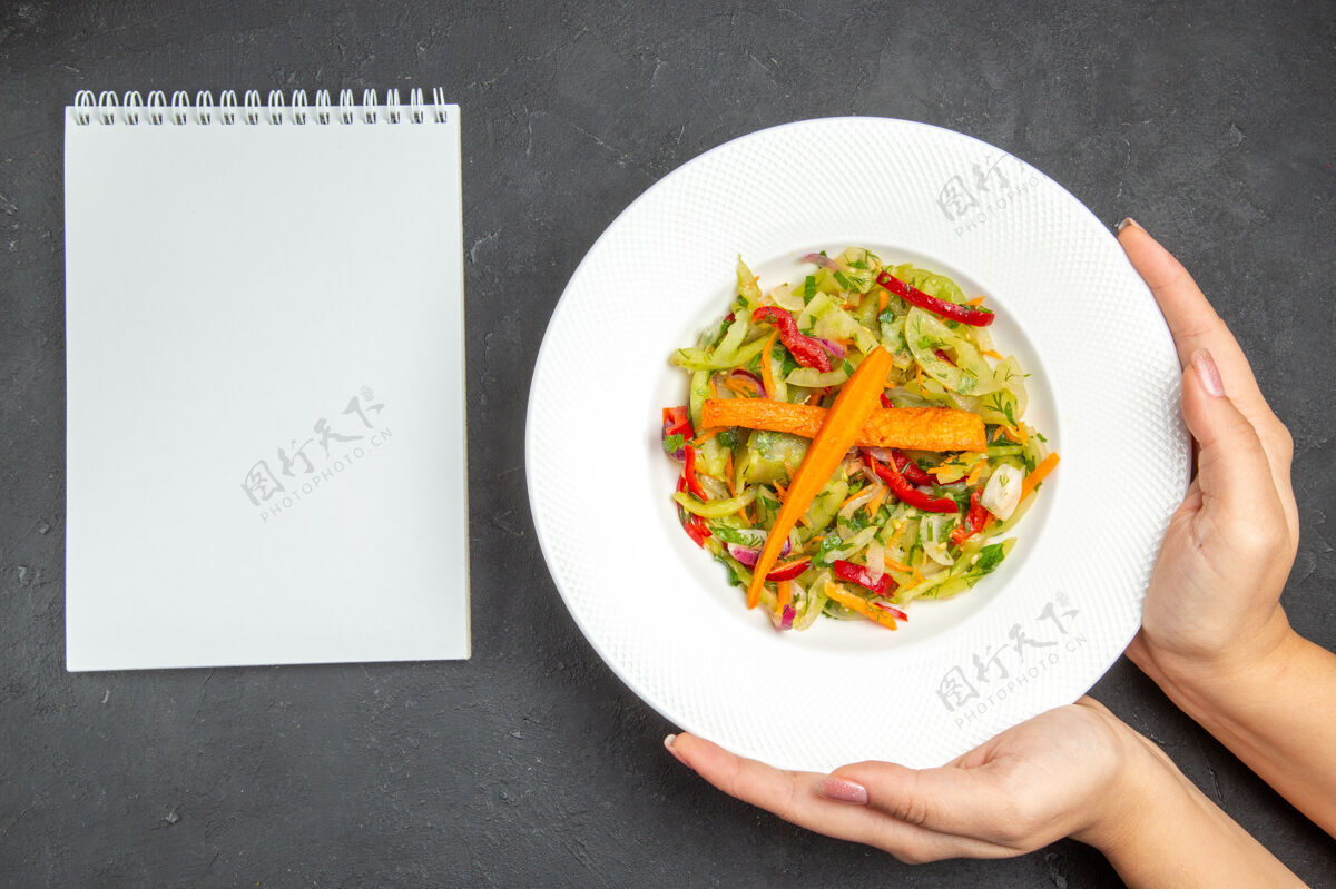 西红柿顶部特写视图沙拉盘的开胃沙拉与蔬菜在手白色笔记本晚餐特写美食