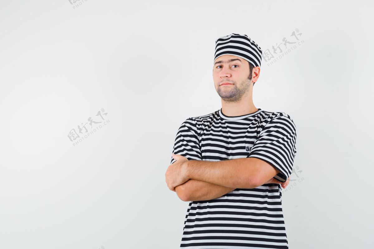 男人身穿t恤 戴着帽子 双臂交叉站着 看上去很自信的年轻男性 正面视图脸商人帽子