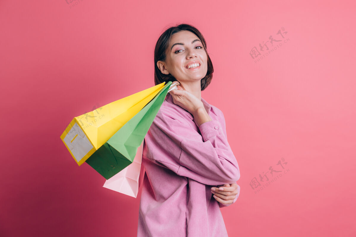 人物背景上穿着休闲毛衣的女人拿着五颜六色的包快乐地享受购物粉色销售客户