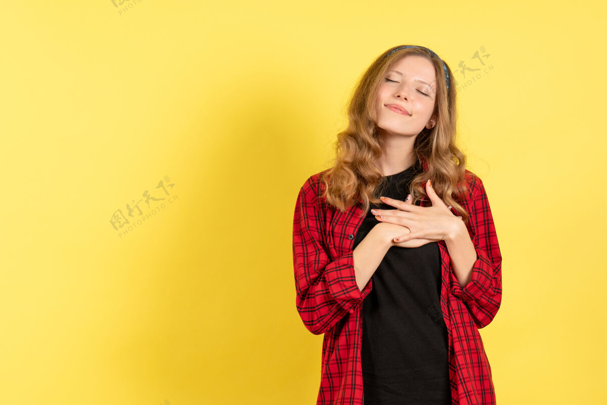 观点正面图身着红色格子衬衫的年轻女性在黄色背景上摆姿势女孩情感色彩人模女人年轻女性情绪女孩