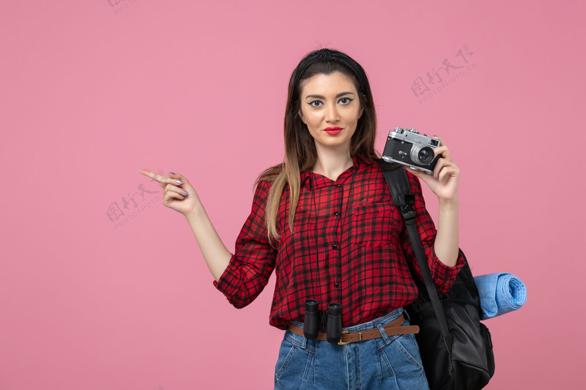 微笑正面图：年轻女性用相机在粉色背景上拍照的女性照片模型相机漂亮人