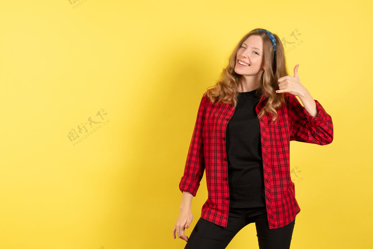 女孩正面图身着红色格子衬衫的年轻女性在黄色办公桌上微笑摆姿势女人人类情感模特时尚女孩情绪人微笑