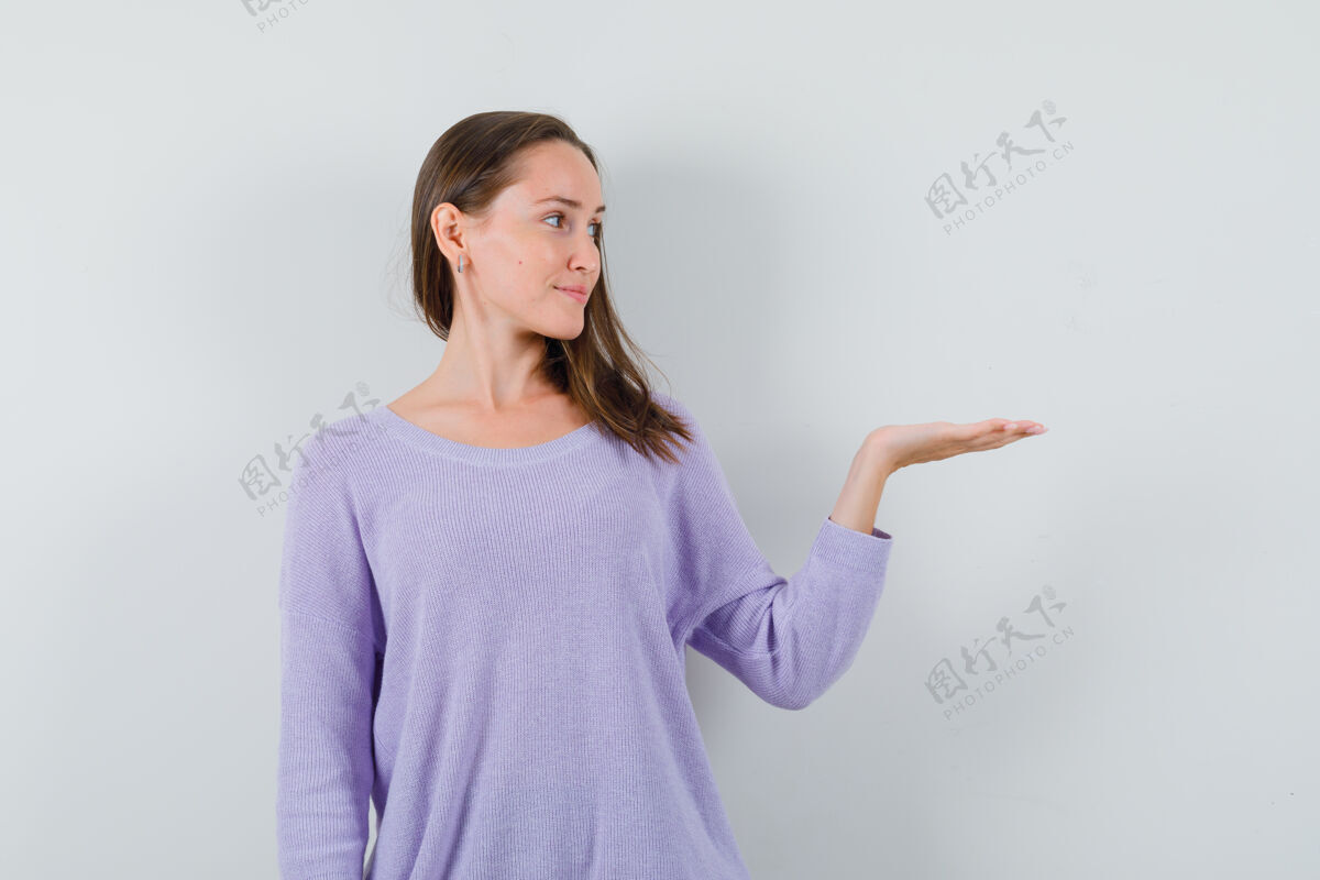 优雅年轻的女人把她张开的手掌放在一边 穿着淡紫色的衬衫 看上去很高兴衬衫漂亮一边