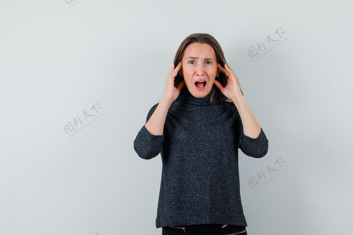 女性一个穿着衬衫的年轻女人 手拉着耳朵 神情焦急手耳朵靠近