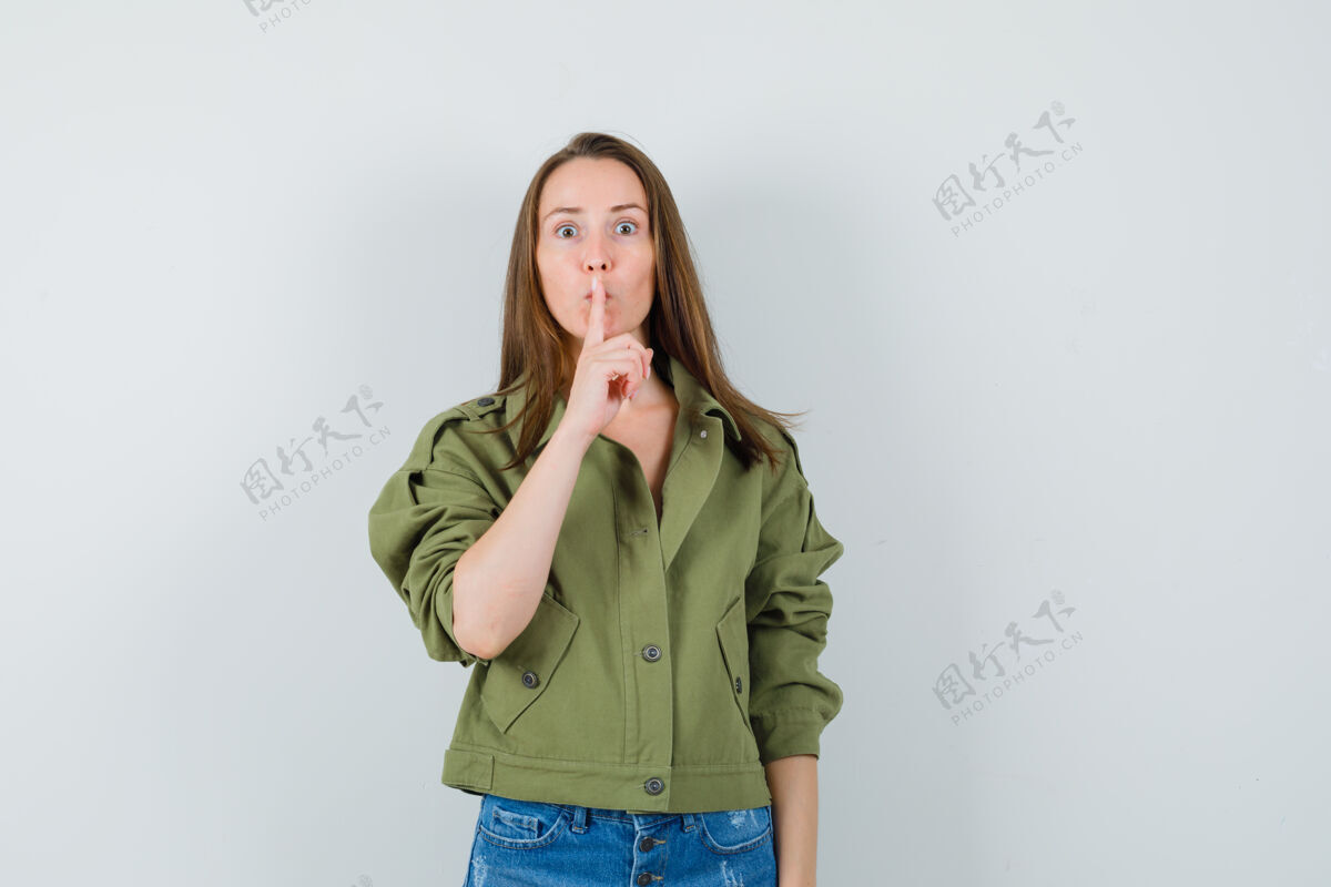 积极一位身穿绿色夹克短裤的年轻女士 表现出沉默的姿态 看上去很小心展示女性休闲